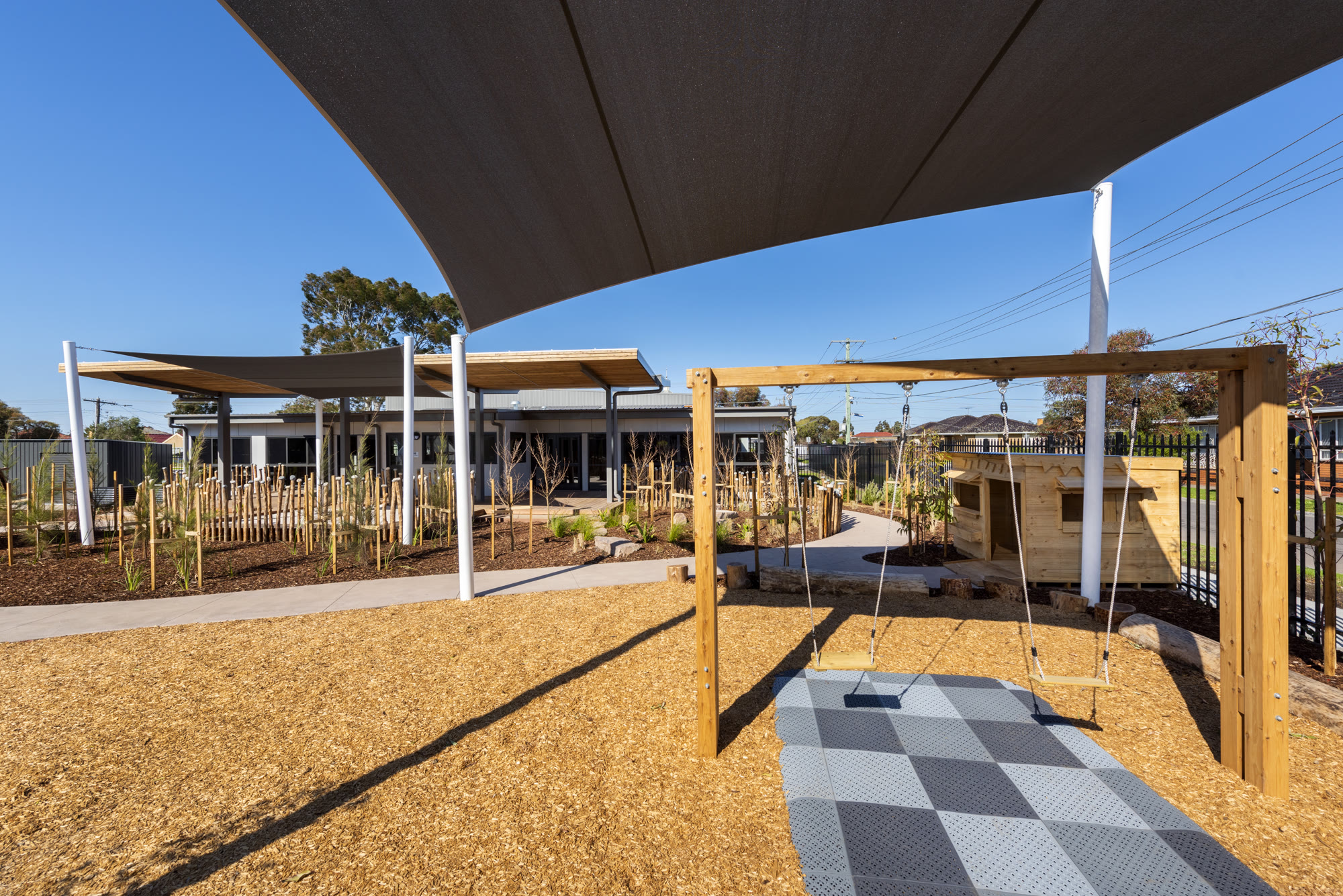KOSS 2021 — swing set and cubby house within native garden play area